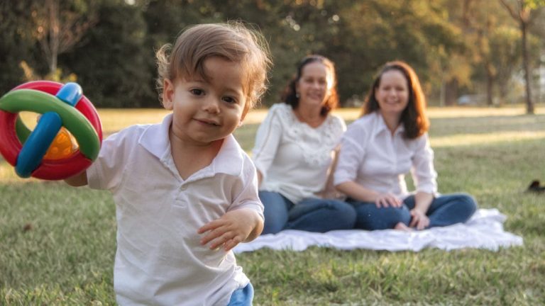 A joyful family enjoying a picnic in the park with a playful toddler in the foreground.
