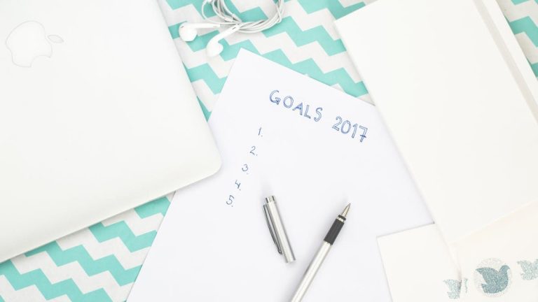 Photo of a workspace featuring a notepad labeled Goals 2017, pen, and laptop for planning.